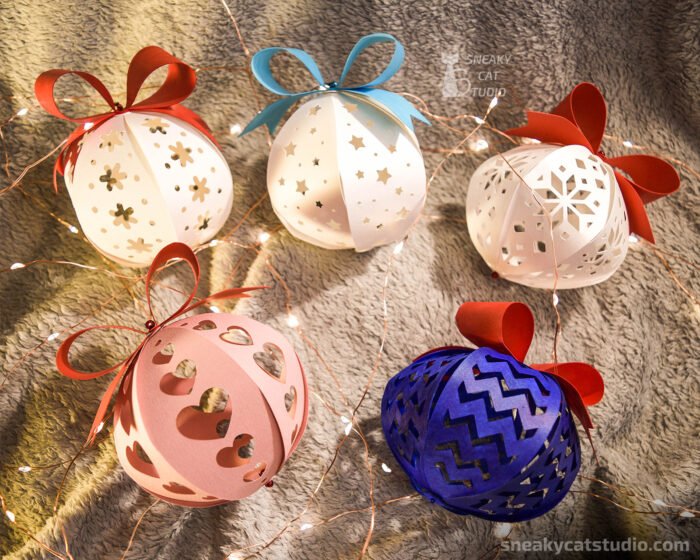 5 paper Christmas balls of different colors on a grey background with light