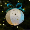 White paper Christmas ball with star pattern on the Christmas tree with light front view