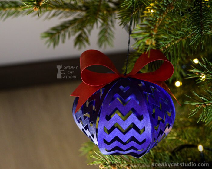 Blue paper Christmas ball with geometric pattern on the Christmas tree with light