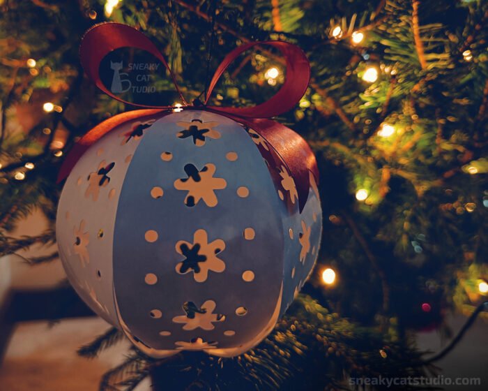 White paper Christmas ball with flower pattern on the Christmas tree with light