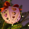 Pink paper Christmas ball with heart pattern on the Christmas tree with light bottom view