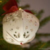 White paper Christmas ball with geometric pattern on the Christmas tree with light bottom view