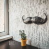 Paper Black Mustache on the gray wall with plant on the table main view