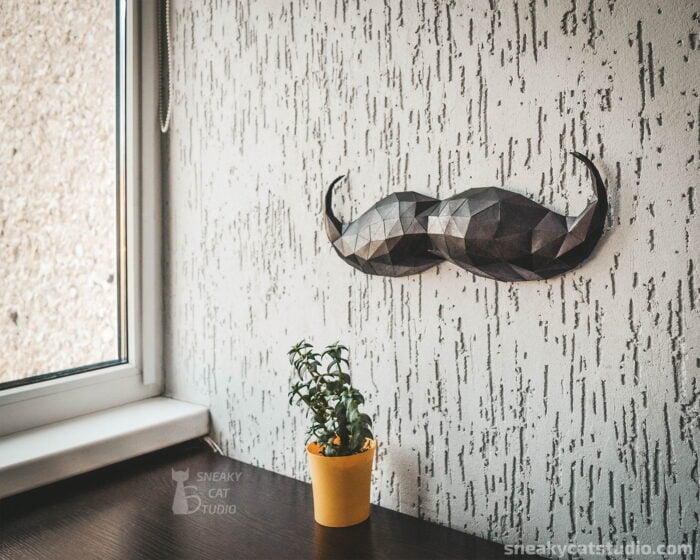 Paper Black Mustache on the gray wall with plant on the table main view
