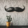 Paper Black Mustache on the gray wall with plant on the table front view