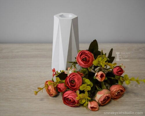 Geometric white vase with flowers near on the table on a light background front view